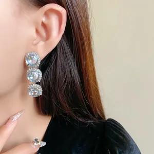 Detailed close-up of elegant three-tier crystal halo earrings on model for formal wear