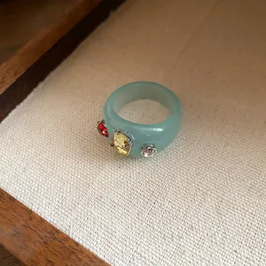 Macro view of light blue chunky resin ring featuring red and yellow rhinestones