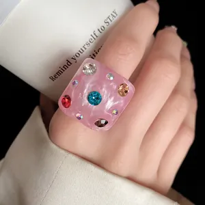 Close-up macro detail of a chunky square pink resin ring with colorful embedded rhinestones