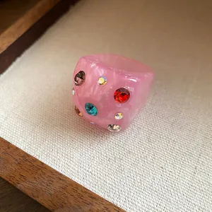 Detail view of a chunky pink resin ring featuring multi-colored embedded rhinestones