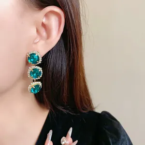 Close-up of elegant emerald green triple drop earrings with rhinestone accents on model