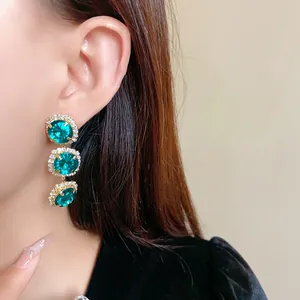 Elegant emerald green three-tier dangling earrings with detailed rhinestone halo