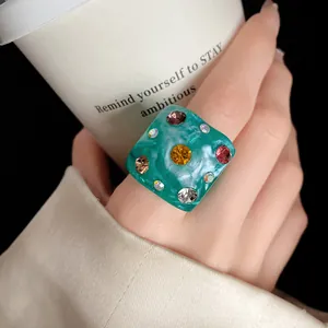 Detailed view of a green square resin ring with multi-colored rhinestone accents