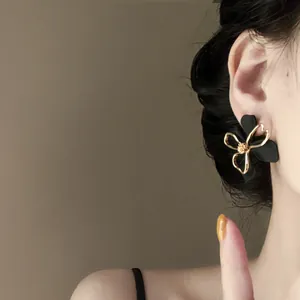 Detailed close-up of a French vintage matte black floral earring with gold wire outline.