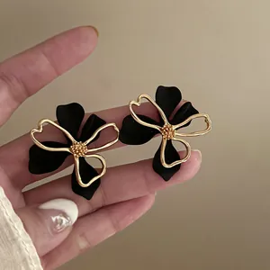 Close-up detail of French vintage black matte flower stud earrings with gold trim