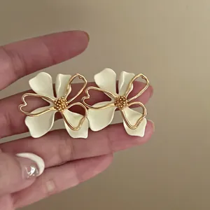 Detailed view of French vintage floral stud earrings with cream petals and gold accents.
