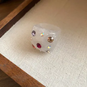 Detailed view of a white resin ring with vibrant multi-colored embedded rhinestones.