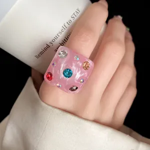Detail close-up of a pink square resin ring featuring colorful embedded rhinestones.