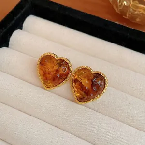 Dettaglio di orecchini vintage a cuore con resina ambra e bordo dorato testurizzato