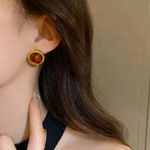 Orecchini vintage con bordo dorato e resina ambrata indossati su orecchio modella