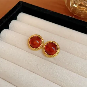 Dettaglio di orecchini a lobo vintage rotondi con resina ambra e bordo dorato