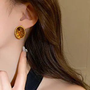 Primo piano di orecchini vintage ovali ambrati con bordo dorato indossati da una modella