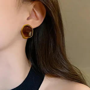 Primo piano di orecchini a perno ovali vintage marroni con bordo dorato su modella