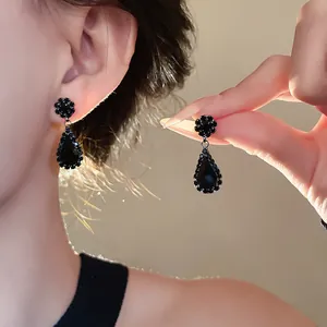 Detailed close-up view of elegant black teardrop drop earrings with rhinestone edges