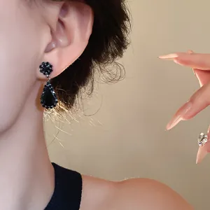 Close-up detail of a black rhinestone water drop pendant earring on a model ear