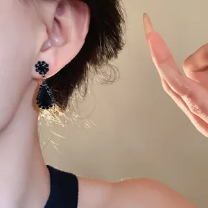 Detailed macro shot of vintage black rhinestone teardrop earrings on a female model