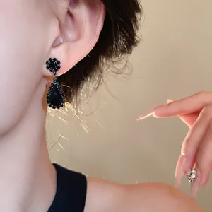 Detail view showing elegant black teardrop earrings with shiny rhinestones worn on the ear
