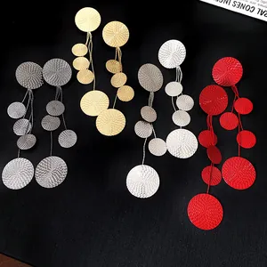 Detail view of long tassel earrings with textured circular disks in multiple colors