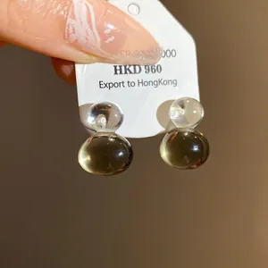 Close-up of gourd-shaped jelly brown and clear resin earrings with silver needles