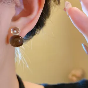 Close-up of brown and transparent resin jelly gourd earrings with minimalist style
