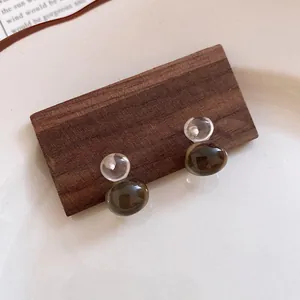 Macro detail of resin jelly color gourd earrings with silver needles on dark wood base