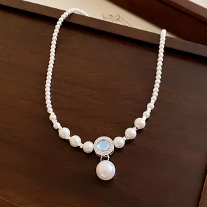 Détail d'un collier de perles vintage français avec un pendentif en pierre bleue et zircons.