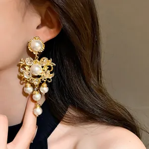 Close-up of ornate gold vintage pearl earrings worn by a model