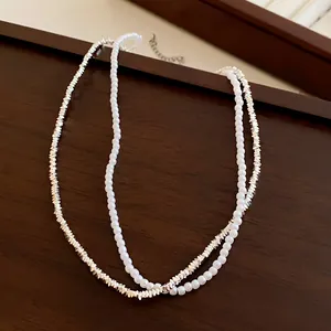 Gros plan détaillé d'un collier double rang en perles et perles de cœur argentées.