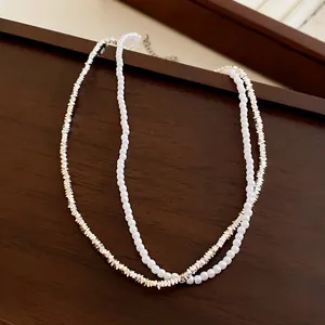 Gros plan d'un élégant collier à deux rangs avec perles blanches et perles argentées.