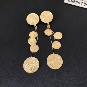 Detailed view of textured golden circular tassel earrings with elegant silver needle posts