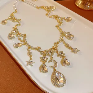Close-up detail of vintage gold necklace featuring heart, moon, and large crystal charms.