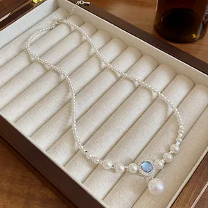 Vue détaillée d'un élégant collier de perles avec pendentif en zircon bleu dans un écrin