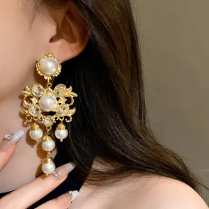Close-up of oversized vintage gold chandelier earring with pearls and rhinestones