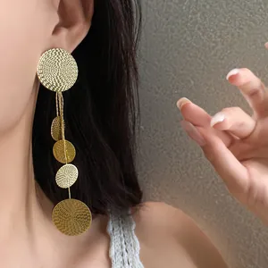 Detailed macro view of golden circular tassel earrings featuring intricate spiral textures