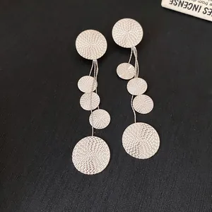 Detailed macro view of silver round dangle earrings with spiral texture and long tassels