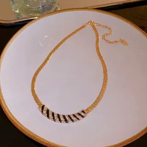 Elegant gold plated curved necklace with black enamel stripes and sparkling rhinestones