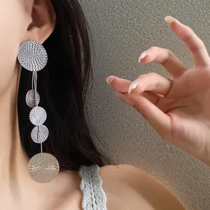 Detailed side view showing a model wearing long textured silver disc tassel earrings