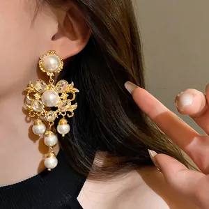 Close-up detail of ornate vintage gold-toned chandelier earrings with white pearls and crystals