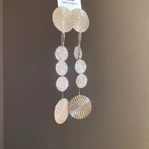 Close-up of long textured metal circular dangle earrings with shimmering finish