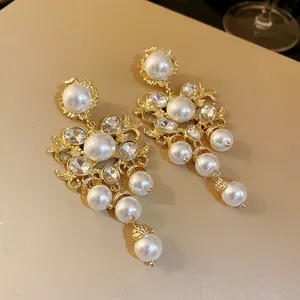 Detailed view of vintage gold earrings with large white pearls and clear crystals.