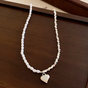 Détail macro du collier rétro français en perles et pendentif cœur en argent sur bois
