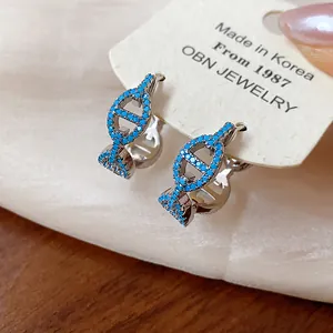 Detail of silver-tone hoop earrings with turquoise zircon pig nose design.