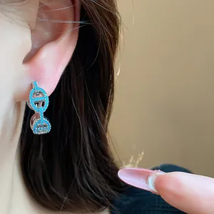 Detailed close-up of silver retro zircon pig nose earrings with blue stones worn on a person's ear