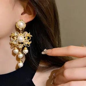 Detailed view of oversized vintage baroque gold earrings with pearls and crystals.