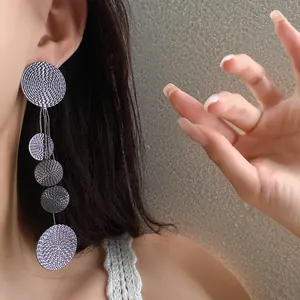 Close-up view of elegant long dangle earrings featuring textured silver circular discs