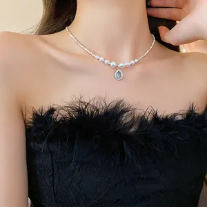 Gros plan d'un collier ras du cou en perles élégantes avec pendentif goutte bleue