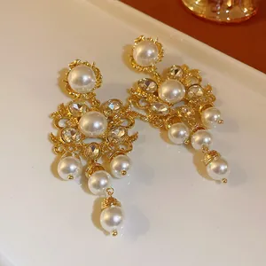 Close-up of vintage ornate gold earrings featuring elegant white pearls and crystals