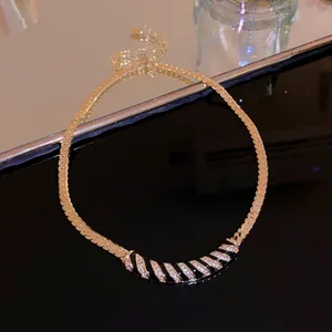 Detail shot of a gold-plated arc necklace with black enamel and pavé rhinestones