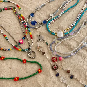 Colección de collares de perlas Y2K de colores con dijes de corazones y flores en papel.