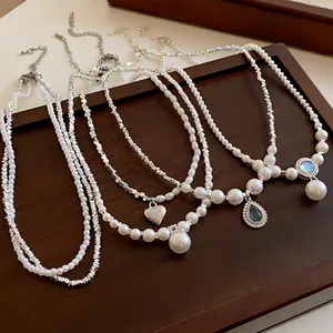 Vue détaillée de colliers assortis en perles et zircons avec pendentifs en cœur et pierres.
